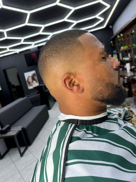 Mann mit kurzem Haarschnitt und Bart in einem modernen Friseursalon.